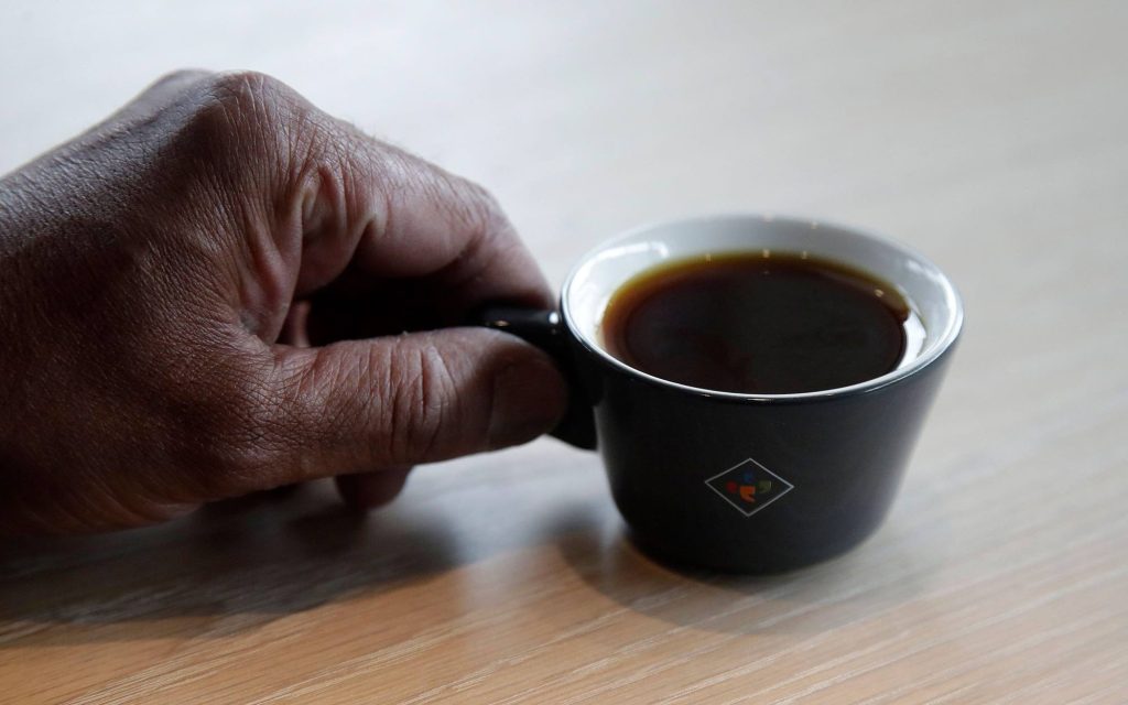 Mão de uma pessoa segurando uma xícara de café