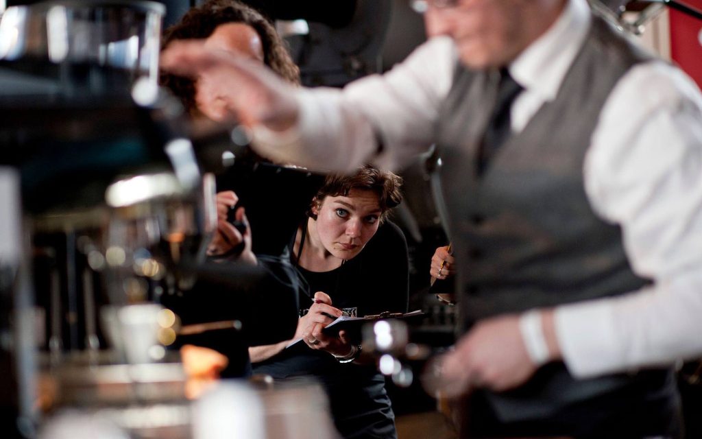 A judge watches a coffee competitor prepare espresso.