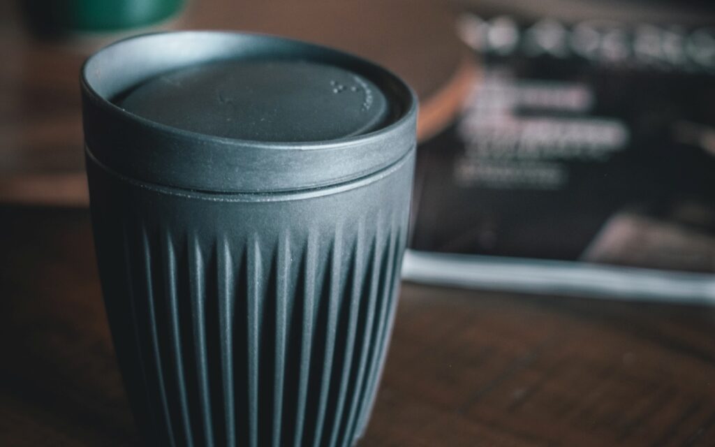 Black HuskeeCup with a lid in a coffee shop.