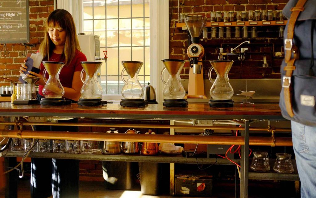 A barista prepares drinks in a café.