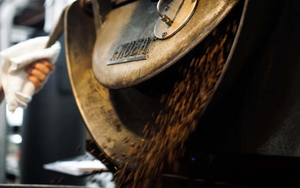 A roaster open a Probat machine after finishing roasting a batch of coffee.