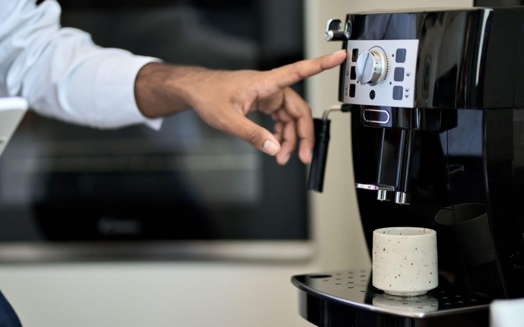 mãos de uma pessoa operando uma máquina superautomática de café