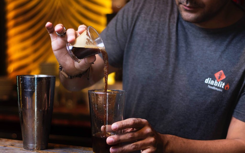 A barista follows an espresso martini recipe at a bar.