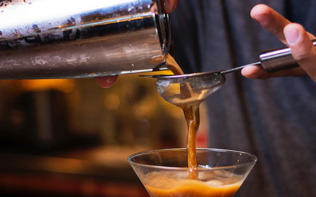 Preparing an espresso martini according to a recipe.