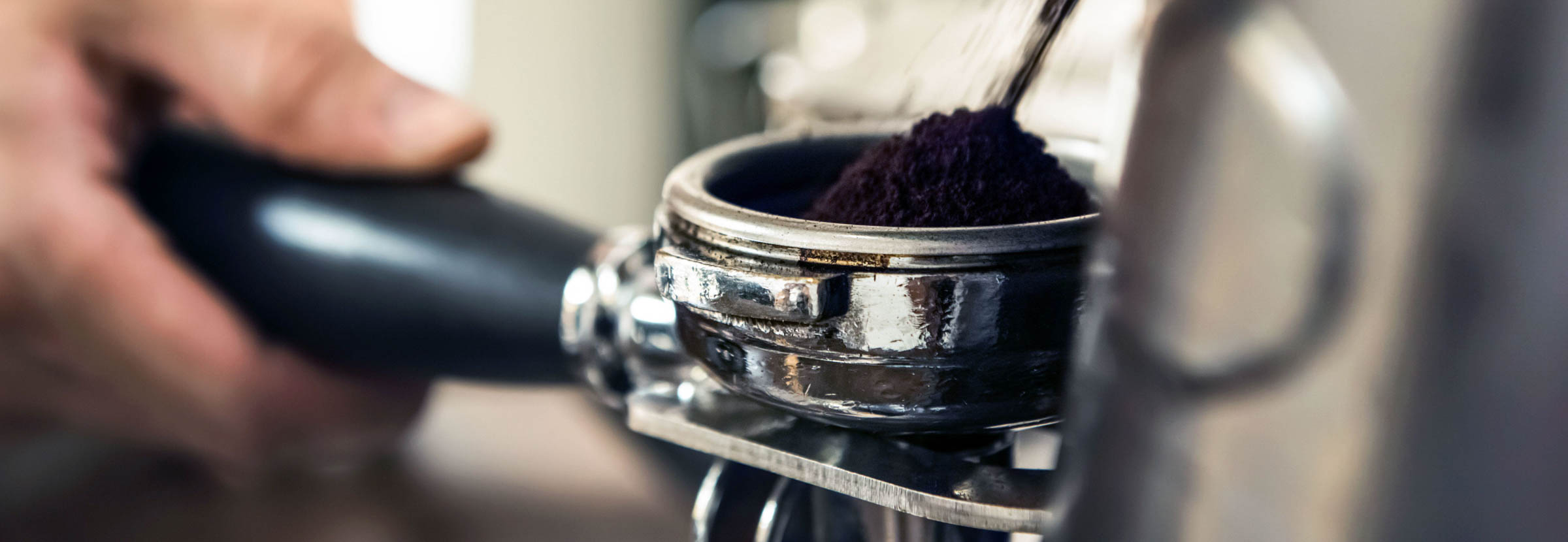 A barista grinds coffee into a portafilter.