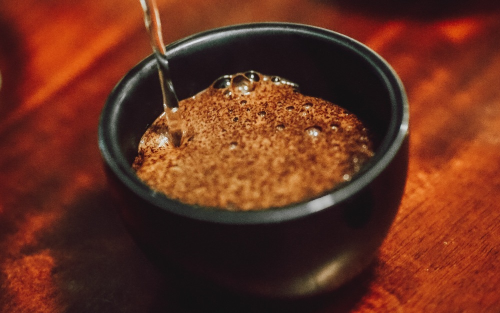 água sendo despejada em uma amostra de cafés numa sessão de cupping para avaliação sensorial