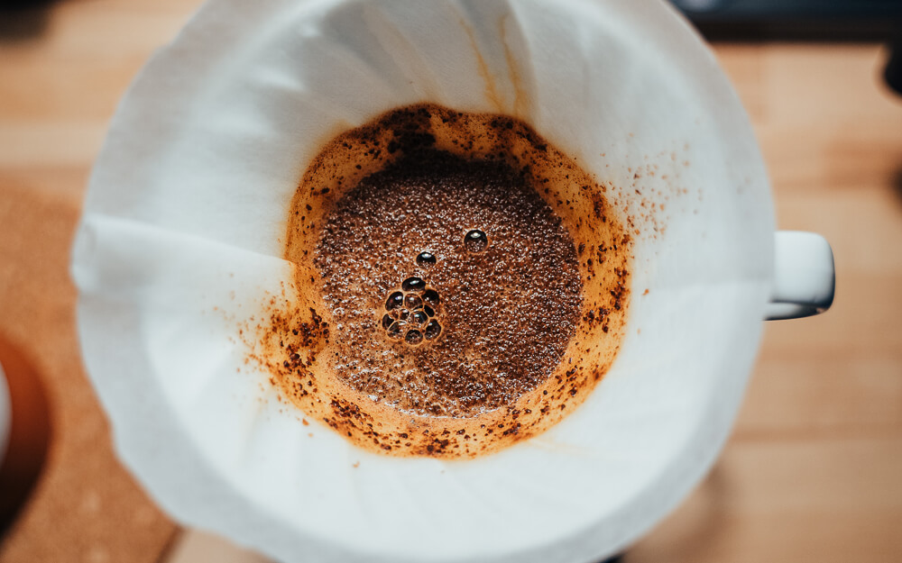 Café sendo preparado num coador de papel, visto de cima.